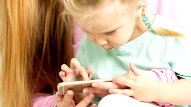 Glückliche-junge-Mutter-und-Tochter-spielen,-zeichnen,-spielen-auf-Ihrem-Smartphone-Zopf-flechten,-zu-lesen.