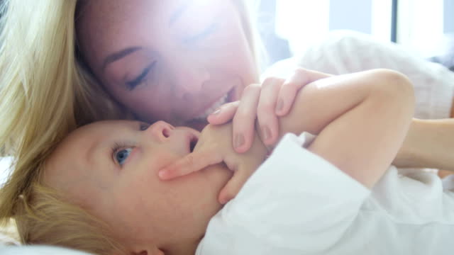 Portrait-of-mother-kissing-baby-daughter-at-home