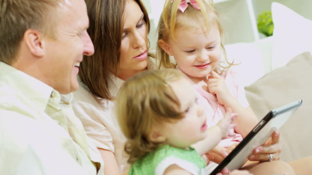 Young-parents-and-kids-playing-online-touchscreen-game