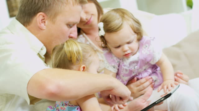 Eltern-und-Mädchen-spielen-auf-Tablet-zu-Hause