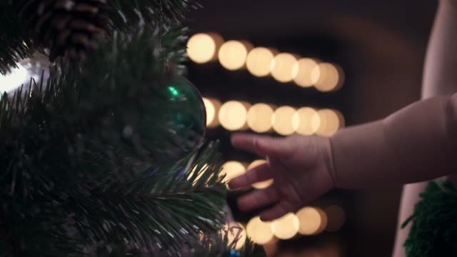 Niño-lindo-en-tapa-rayas-dispara-un-juguete-de-la-bola-verde-de-un-árbol-de-Navidad.-Close-up