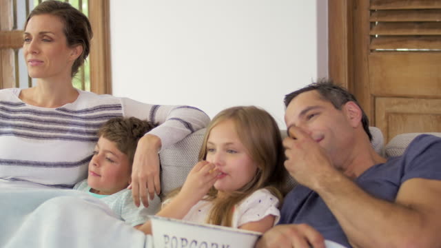 Zeit-mit-der-Familie-zu-Hause-kuscheln-auf-der-Couch-im-Wohnzimmer-mit-Popcorn-einen-Film