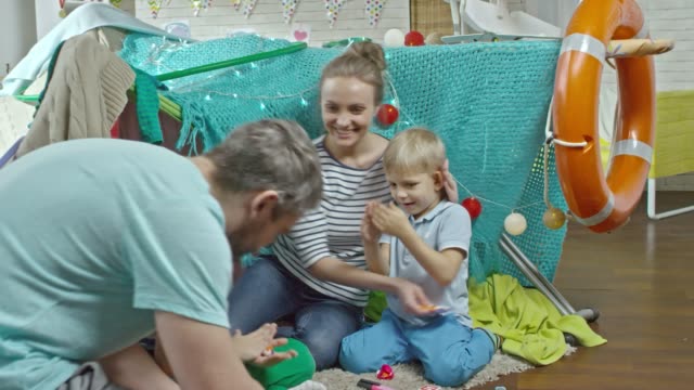 Los-felices-padres-y-dos-niños-pequeños-jugando-con-plastilina-juntos