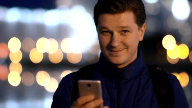 A-young-attractive-man-uses-a-mobile-phone-in-a-night-city.