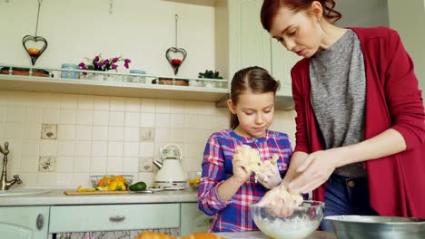Glückliche-Mutter-und-niedliche-Tochter-zusammen-zu-kochen-und-Spaß-unter-Rühren-Teig-in-Händen.-Familie,-Essen,-Haus-und-Leute-Konzept