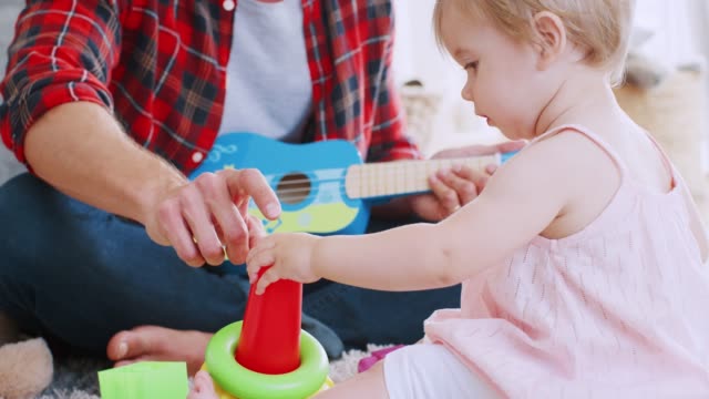 Young-dad-playing-with-his-toddler-daughter-at-home,-close-up