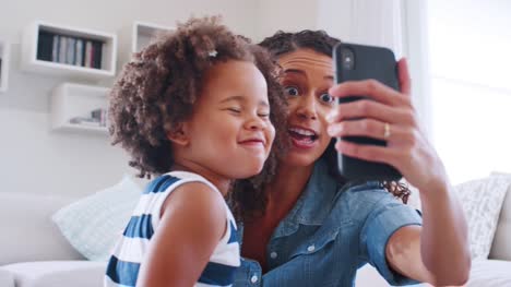 Junge-schwarze-Frau-und-Tochter-nehmen-Selfie-Grimasse