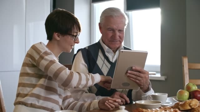 Enkelin-helfen-Großvater-mit-Tablet