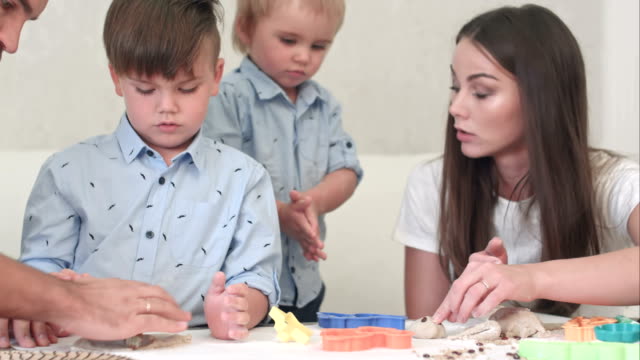 Jóvenes-padres-felices-mostrando-a-sus-hijos-cómo-hacer-galletas