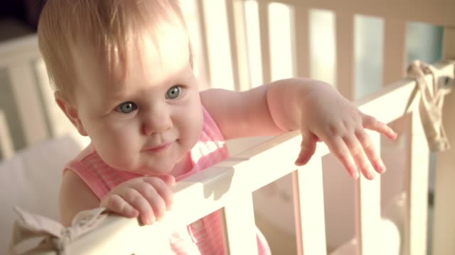 Adorable-baby-reach-out-hand-in-cot.-Little-child-with-interesting-face