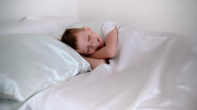 Niño-de-siete-años-sólo-se-despertó-y-se-ríe-mientras-se-está-acostado-en-la-cama.