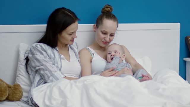 Happy-Female-Couple-in-Bed-with-Cute-Baby
