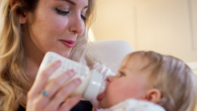 Mother-In-Nursery-Feeding-Baby-Daughter-From-Bottle