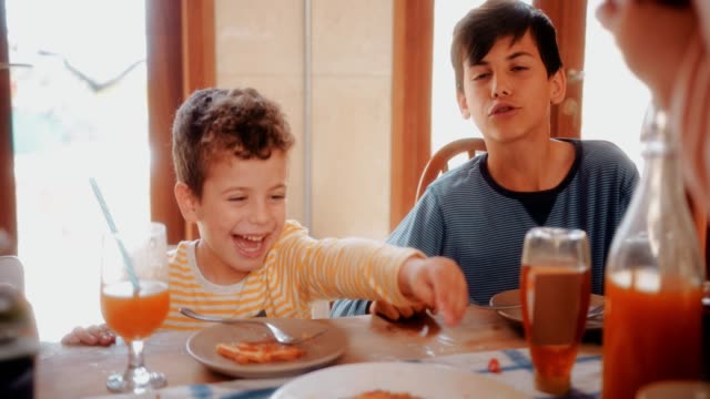 Young-boy-having-fun-eating-healthy-breakfast-with-family