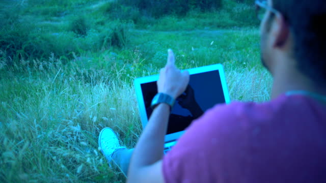 Close-up,-Reflection-in-the-Laptop-Screen,-Indian-Male-Emotionally-Talking-on-the-Phone-Kneeling-Laptop-Sitting-In-the-Evening-on-the-Grass-at-Summit-Hill