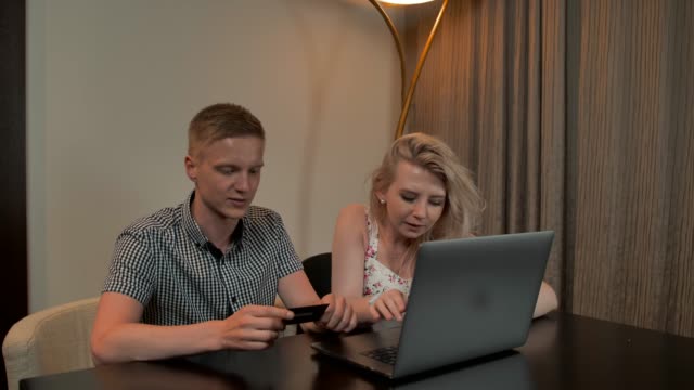 Attraktiver-Mann-und-ein-Mädchen-sitzen-auf-den-Coucand-online-Shop-mit-Kreditkarte-auf-dem-Laptop-notebook