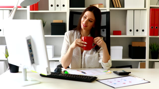 businesswoman-with-cup-looking-in-monitor-in-office