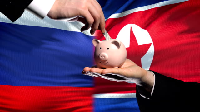Russland-Investitionen-in-Nordkorea-Hand,-Geld-im-Sparschwein-Flagge-Hintergrund