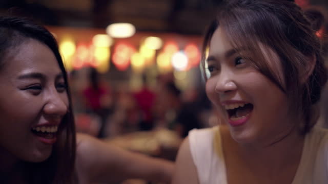 Viajero-mochilero-mujeres-asiáticas-lesbianas-lgbt-par-de-viajes-en-Bangkok,-Tailandia.-Consumo-de-alcohol-o-cerveza-con-los-amigos-y-tener-parte-en-el-camino-de-Khao-San.