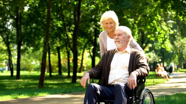 Reife-Frau-kümmert-sich-um-ihren-geliebten-Mann-im-Rollstuhl,-glückliche-Ehe