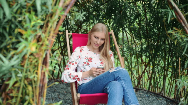 Young-woman-using-smartphone-in-plant-gazebo