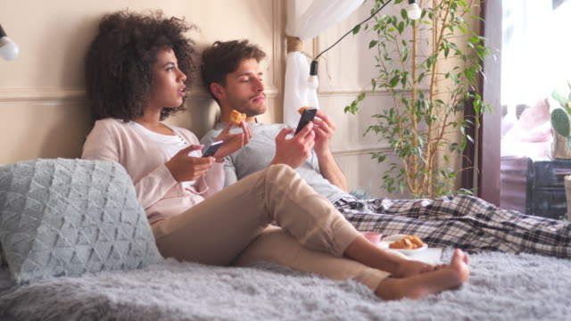 Couple-using-mobile-phone-while-having-breakfast-in-bed