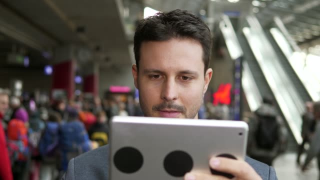 Hübscher-junger-Geschäftsmann,-Verfassen-von-Texten-auf-digitale-Tablet-im-öffentlichen-Raum