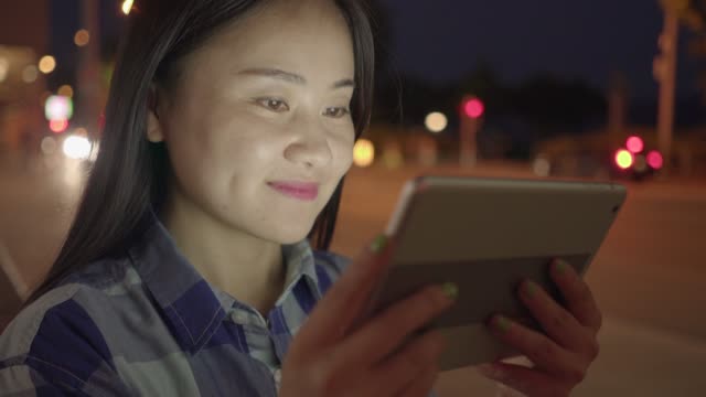Joven-asiática-con-tableta-en-calles-de-la-ciudad