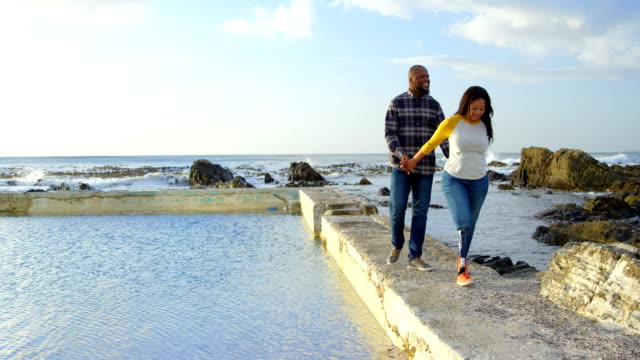 Happy-couple-walking-with-hand-in-hand-on-pier-4k