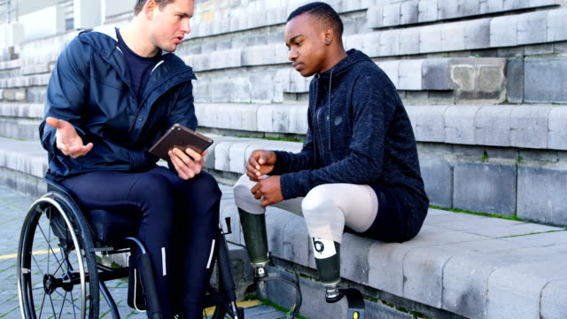 Zwei-behinderte-Leichtathletik-diskutieren-über-digital-Tablette-4k