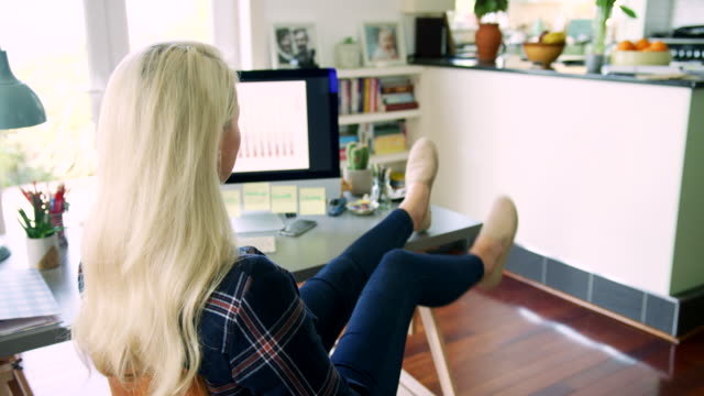 Attraktive-blonde-Geschäftsfrau-setzen-ihre-Füße-am-Schreibtisch
