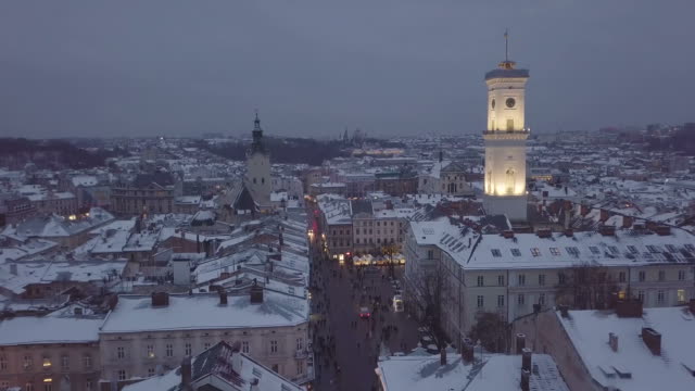 Lviv,-Ucrania---25-de-diciembre-de-2018.-Tiro-de-Arial.-Invierno.-Calle-plaza-Rynok.-Feria-de-Navidad.-Ayuntamiento-de-Lvov.-Personas-están-caminando-en-el-centro-de-la-ciudad.-Adornos-navideños-y-luces.-Noche