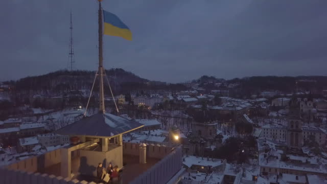 LVOV,-UKRAINE.-Panorama-of-the-ancient-city.-Camera-moves-near-Ukrainian-Flag.-Ukraine-Lviv-City-Council,-Town-Hall.-The-roofs-of-old-buildings.-Aerial,-drone-view.-Winter-night