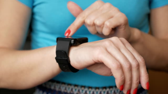 Frau-mit-ihrem-Touchscreengerät-tragbare-Technologie-Smartwatch.-Mädchen-machende-Gesten-auf-einem-tragbaren-Smartwatch-Computergerät-hautnah.