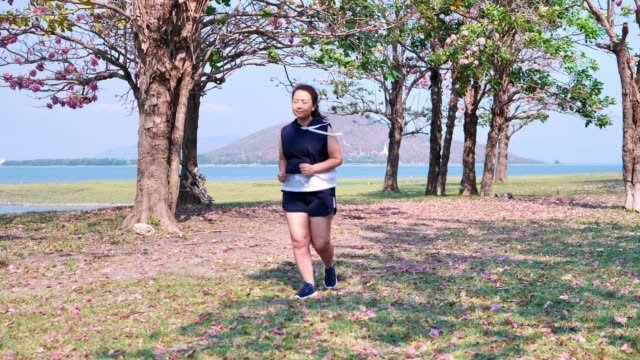 An-Asian-woman-jogging-in-natural-sunlight-in-the-morning.
She-is-trying-to-lose-weight-with-exercise.--concept-health-with-exercise.-Slow-Motion