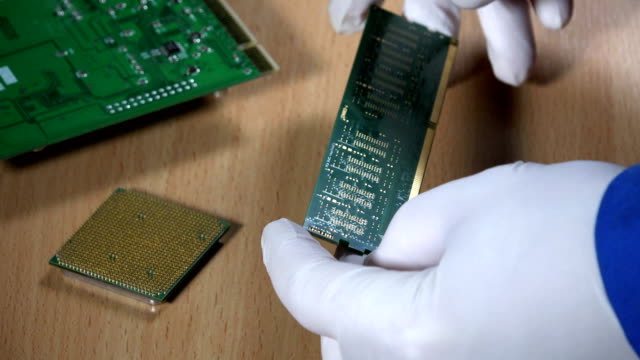 computer-specialist-examine-RAM-memory-module-on-wooden-background