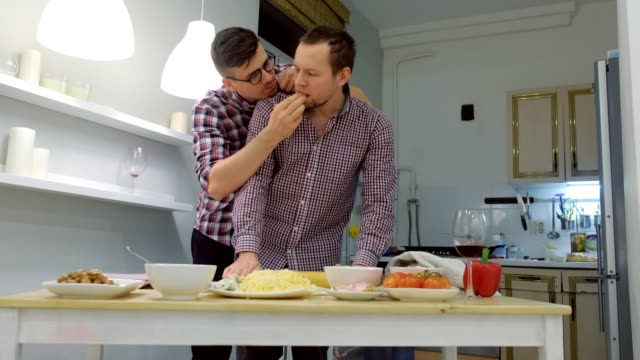 Un-par-de-hombres-gay-se-juntan-la-masa-de-pizza-abrazando.