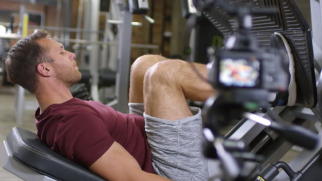 Entrenador-de-gimnasia-mostrando-pierna-Press-ejercicio-en-la-cámara