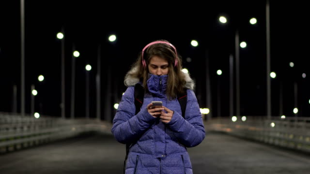 La-chica-del-teléfono-inteligente-está-en-la-ciudad-por-la-noche,-hablando-en-las-redes-sociales