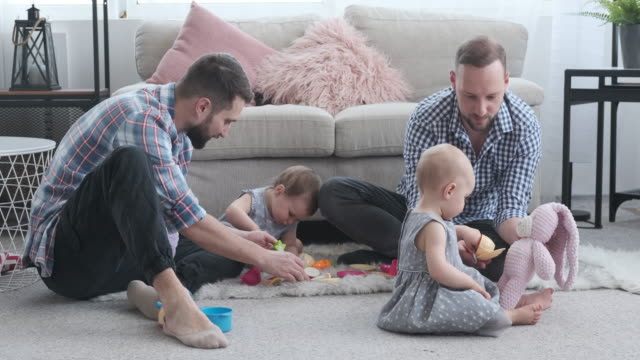 Two-dads-and-baby-daughter-playing-with-toy-at-home