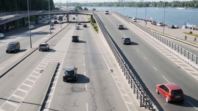Aerial-view-from-Metro-Bridge,-also-known-as-Mostmetro,-heavy-traffic-in-the-day,-Dnipro-river-and-city-skyline.-Big-city-life-concept.-Ukraine,-Kyiv,-01.06.2019