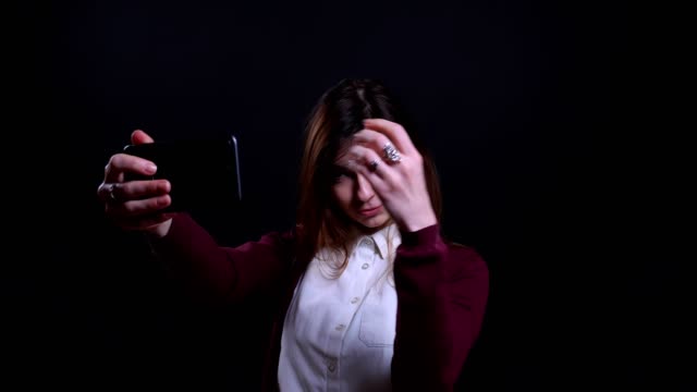 Retrato-de-joven-morena-de-negocios-haciendo-hermosas-selfie-fotos-en-el-teléfono-celular-felizmente-en-fondo-negro.