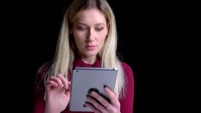 Closeup-portrait-of-young-pretty-caucasian-female-using-the-tablet-getting-excited-and-surprised-while-looking-at-camera