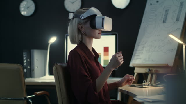 Business-woman-swiping-hands-in-interactive-space-in-night-office