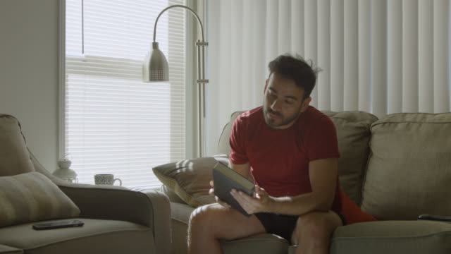 Man-throws-cellphone-in-couch,-then-picks-up-a-book-and-enjoys-it