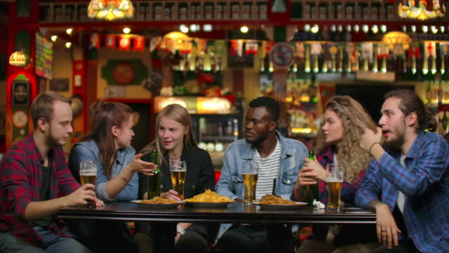 Afroamerikaner-mit-Freunden-an-einer-Bar-trinken-Bier-und-Essen-Chips-mit-Freunden