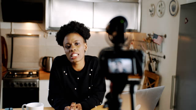 Glückliche-junge-professionelle-afrikanische-Mode-Bloggerin-filmt-Video-Blog-mit-Kamera-zu-Hause-Küche-Zeitlupe.