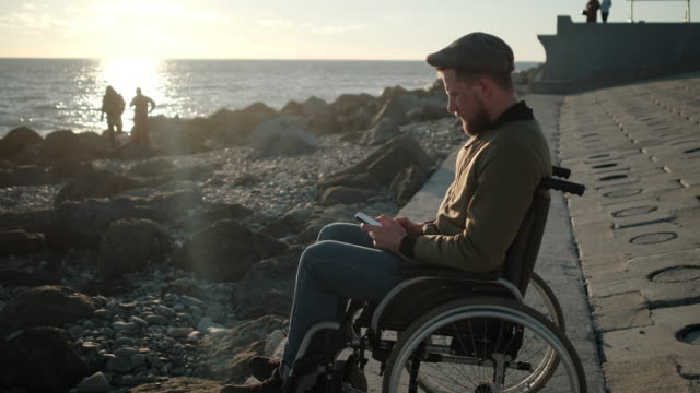 Solitario-discapacitado-con-móvil-cerca-del-mar