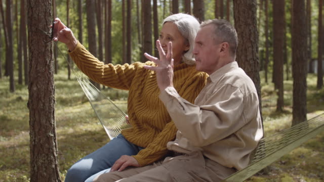 Senioren-sitzen-in-Hängematte-und-sprechen-per-Video