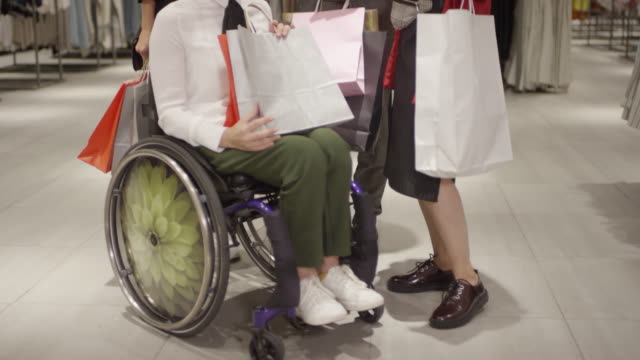 Paraplegiker-Frau-Chatten-mit-Freunden-in-Kleidung-Store